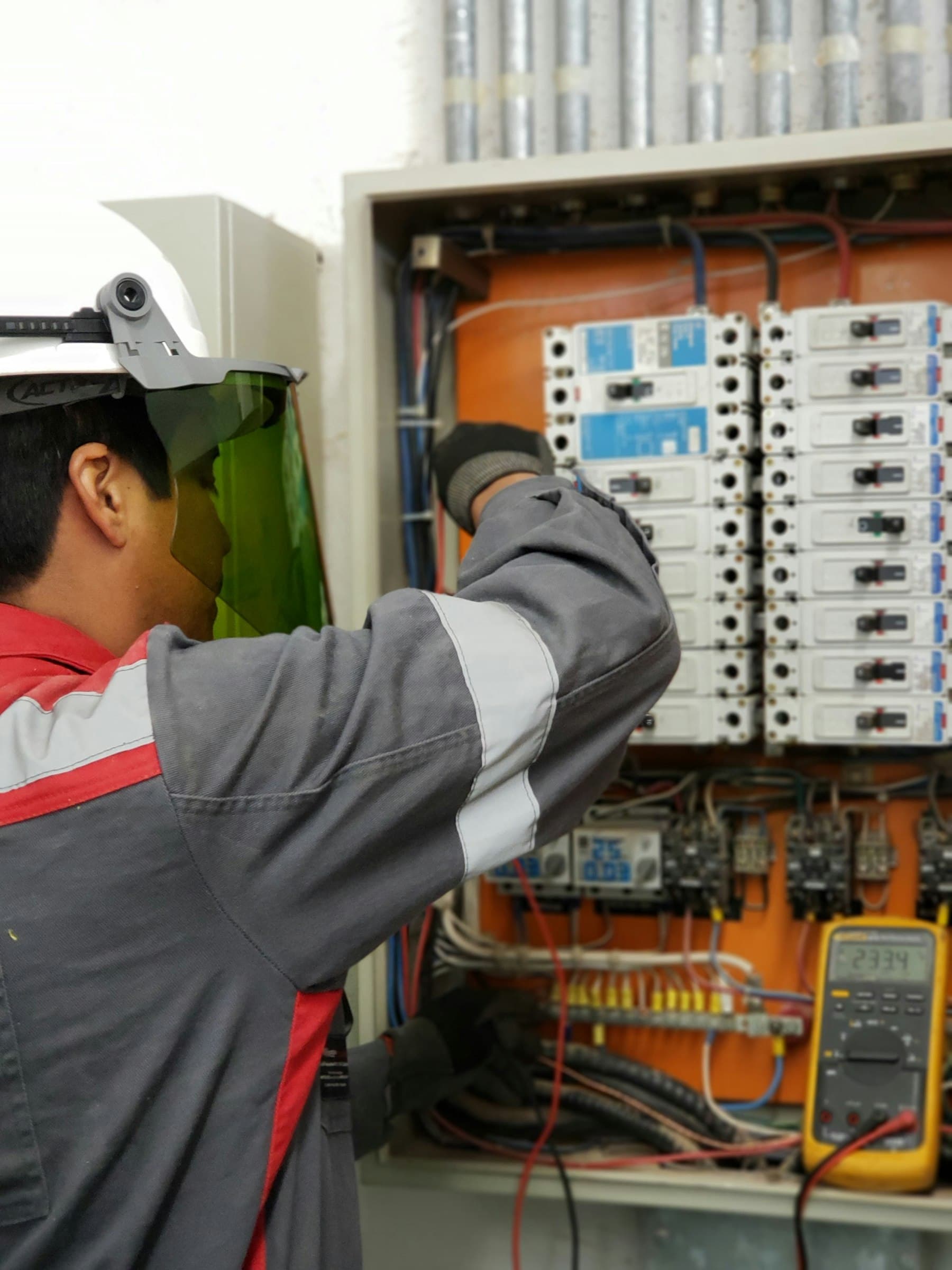 Elektrik panosunda ölçü aletiyle çalışan saha bakım çalışanı